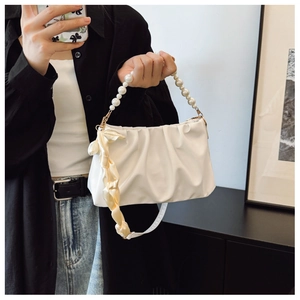 Detail of white pleated handbag with pearl bead handle and elegant champagne ribbon