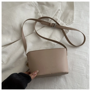 Close-up of beige mini bucket bag with FANYISSA embossing on matte leather texture
