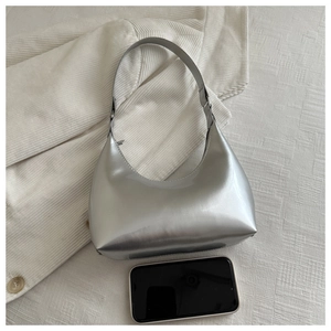 Silver metallic patent leather hobo bag next to a smartphone for size reference