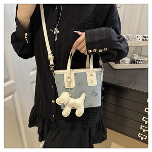 Bolso tipo cubo chic con estampado de mariposas y colgante de perro sobre vestido negro