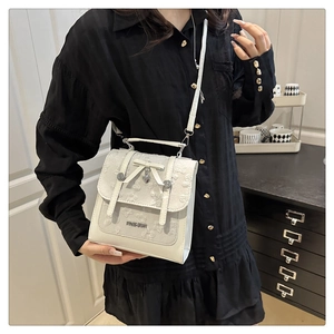 Détail du sac à bandoulière blanc crème avec broderie dentelle, nœud et bijoux cœur
