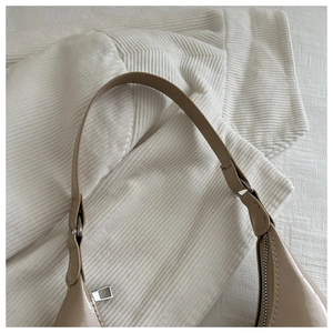 Detail of glossy beige shoulder bag featuring silver zipper and fine stitching accents