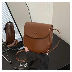 Detail view of a brown saddle bag reflected in a mirror showing side profile and texture