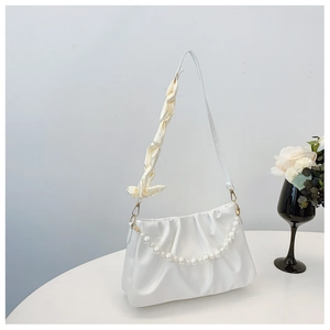 Detailed shot of white ruched cloud bag featuring pearl chain and satin bow strap