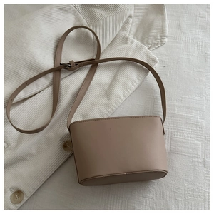 Detailed shot of a beige crossbody bucket bag with fine stitching and adjustable strap