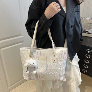 White quilted tote bag with wave embroidery and plush cloud pendant on a model