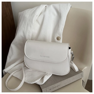 Close-up of minimalist cream white crossbody bag with Fanyissa logo on a textured background