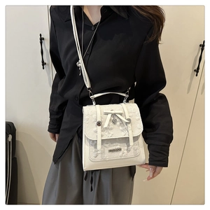 Détail du sac carré blanc en dentelle avec nœud papillon et pendentif cœur élégant