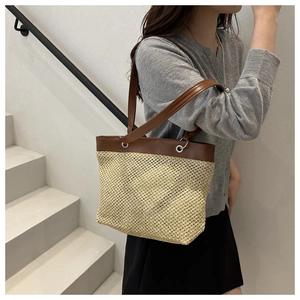 Detail of woven straw texture and brown leather strap on a summer shoulder bag