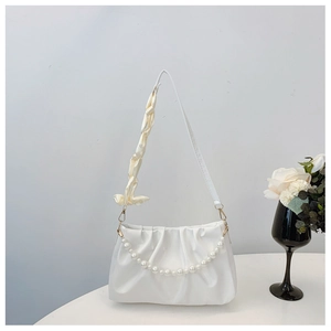 Detail of white pleated cloud bag featuring pearl chain and ribbon-wrapped handle