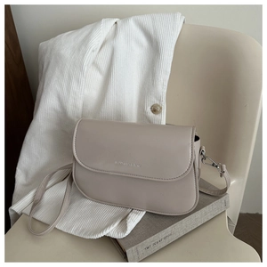 Detail of beige saddle bag showing smooth matte leather texture and silver metal clasp