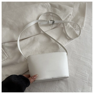 Détail du sac seau en cuir blanc avec logo FANYISSA embossé et bandoulière réglable