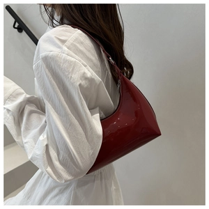 Detail of red patent leather hobo bag with high gloss finish and silver zipper