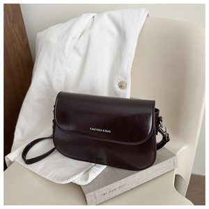 Detail of a dark brown glossy leather shoulder bag with white printed brand logo text