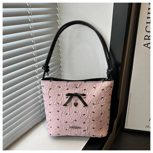Detail of pink bubble texture fabric with black bow patterns and metal heart pendant