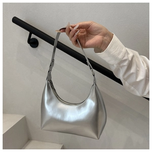 Macro shot of silver crescent underarm bag with glossy metallic finish and sleek zipper