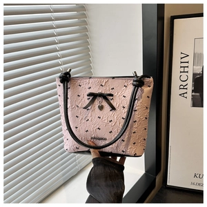 Close-up of pink bucket bag with black bow prints and heart pendant detail