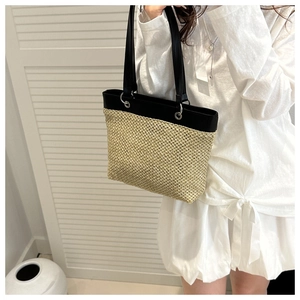 Detail of hand-woven straw tote with black leather handles for summer beach vacations