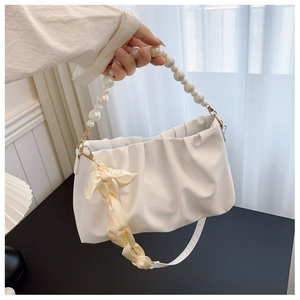 Detailed view of pearl handle and yellow ribbon on white ruched cloud handbag