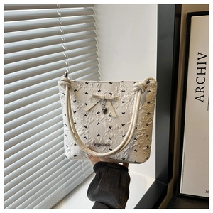 Detail of pleated tote bag with black butterfly prints and a fashion metal logo plate