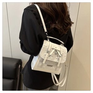 Détails du sac blanc à texture florale avec nœud papillon et breloque clochette