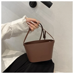Detail of a brown leather bucket bag with embossed logo and elegant smooth texture