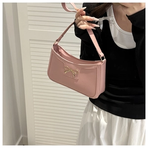 Close-up of pink underarm bag featuring a metallic gold bow buckle and smooth leather texture