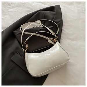 Detail of white glossy crescent shoulder bag with golden chain on grey suit