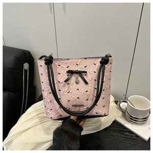 Close-up of pink pleated bucket bag featuring black bow patterns and metal heart charm