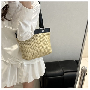 Detail of woven straw tote bag with black leather trim and silver metal eyelet grommets