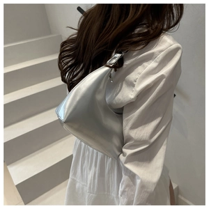Close-up of a silver metallic hobo bag with sleek zipper detail on a white shirt