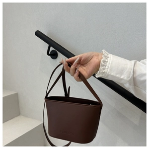 Détail du sac seau en cuir marron foncé avec embossage FANYISSA et poignée de transport