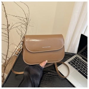 Close-up of brown glossy leather saddle bag with Fanyissa and Bag silver logo detail