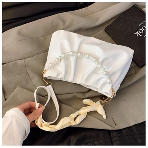Detail of white pleated cloud bag featuring premium pearl handle and yellow silk scarf