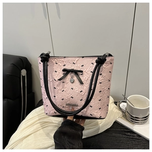 Dettaglio borsa rosa testurizzata con fiocco nero e ciondolo a forma di cuore