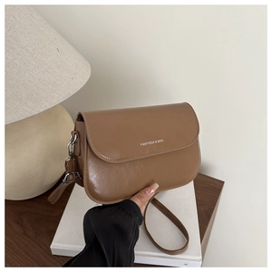 Close-up of caramel brown leather handbag with FANYISSA & BAG logo and gold buckle