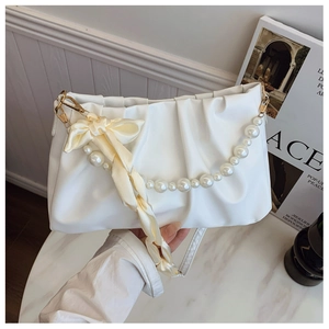 Detail of white ruched cloud bag with pearl handle and beige silk bow decoration