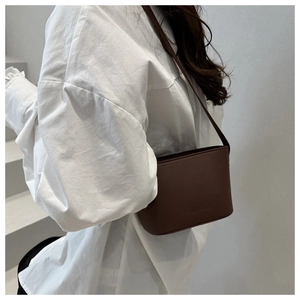 Close-up of Fantissa embossed logo on dark brown leather square shoulder bag worn by model
