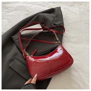Detail of dark red patent leather hobo bag with gold hardware and white text print