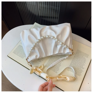 Close-up of pearl handle and pleated cloud bag with yellow silk scarf accessory
