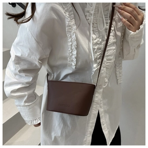 Detail of dark brown leather bucket bag with embossed logo and slim shoulder strap