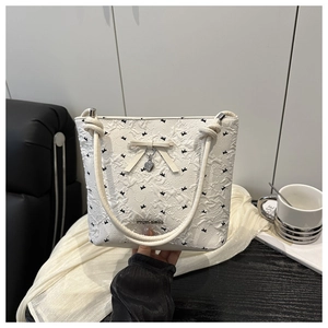 Dettaglio della borsa a secchiello bianca con stampe di farfalle e ciondolo a cuore in metallo