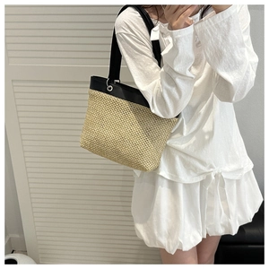 Detail of hand-woven straw tote with black leather trim and silver metal eyelet