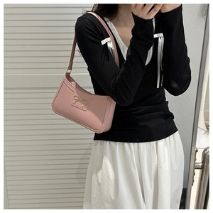 Dettaglio della borsa sottobraccio in pelle rosa con fiocco dorato su modella