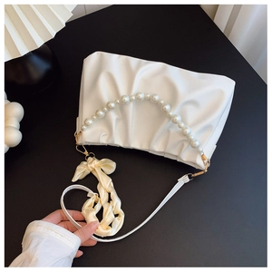 Detail of white pleated cloud bag with pearl handle and yellow satin ribbon scarf