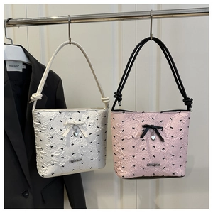 Detail of bubble texture fabric with bow print and heart pendant on shoulder bag