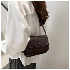 Detail of a deep coffee leather crossbody bag with FANYISSA & BAG logo and glossy finish