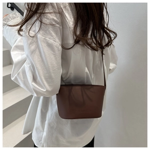 Détail du sac seau marron minimaliste avec logo embossé et texture en cuir mat