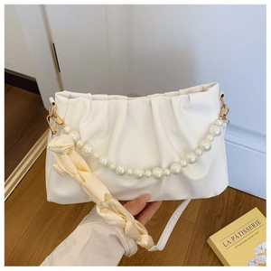 Close-up of white ruched cloud bag with pearl handle, yellow silk scarf, and gold hardware