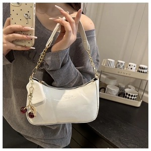 Detail of white glossy leather hobo bag with gold chain strap and cherry charm